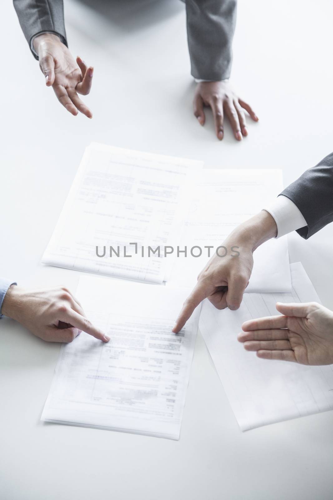 Four business people arguing and gesturing around a table during a business meeting, hands only  by XiXinXing