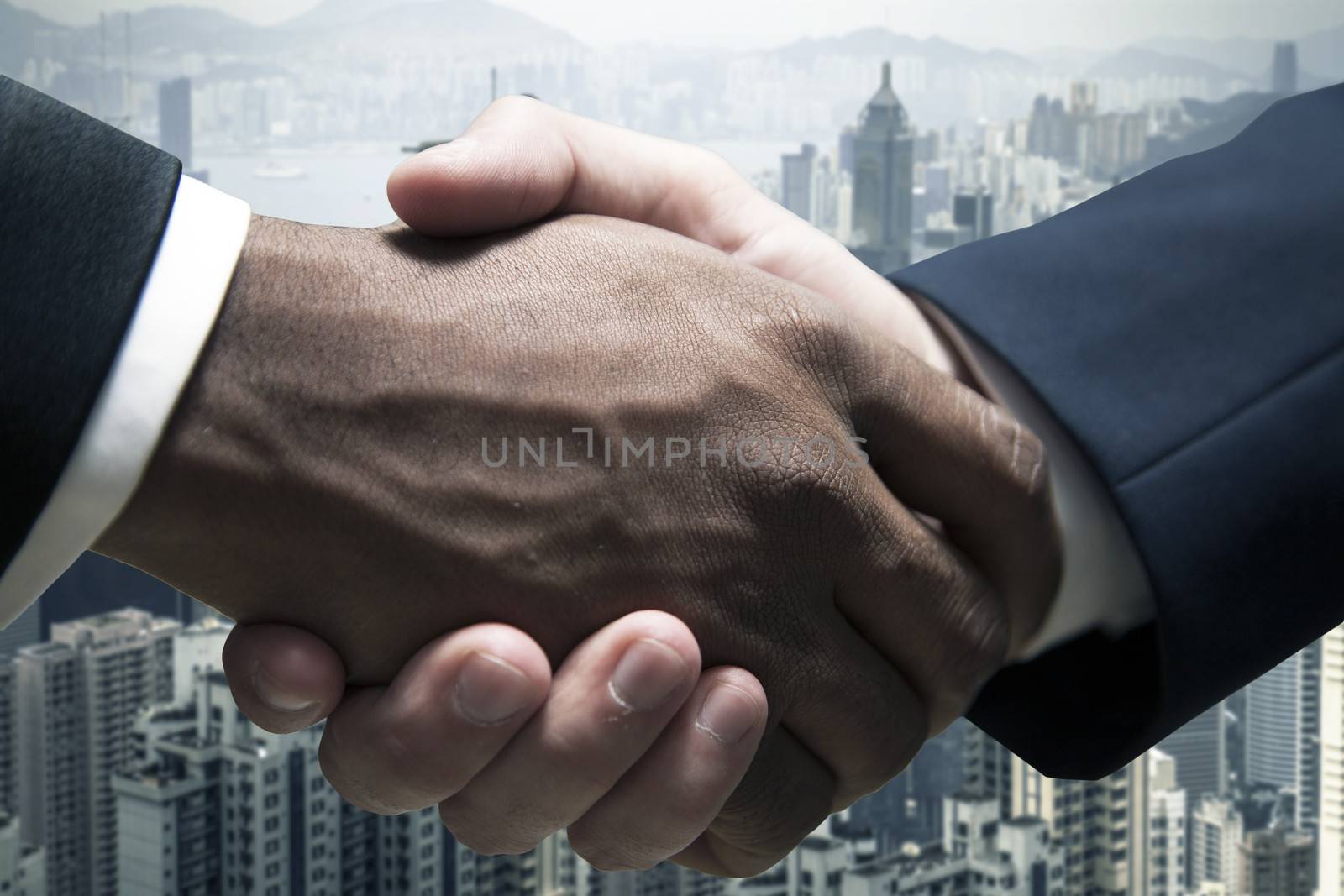 Close up of businessmen shaking hands with cityscape in the background