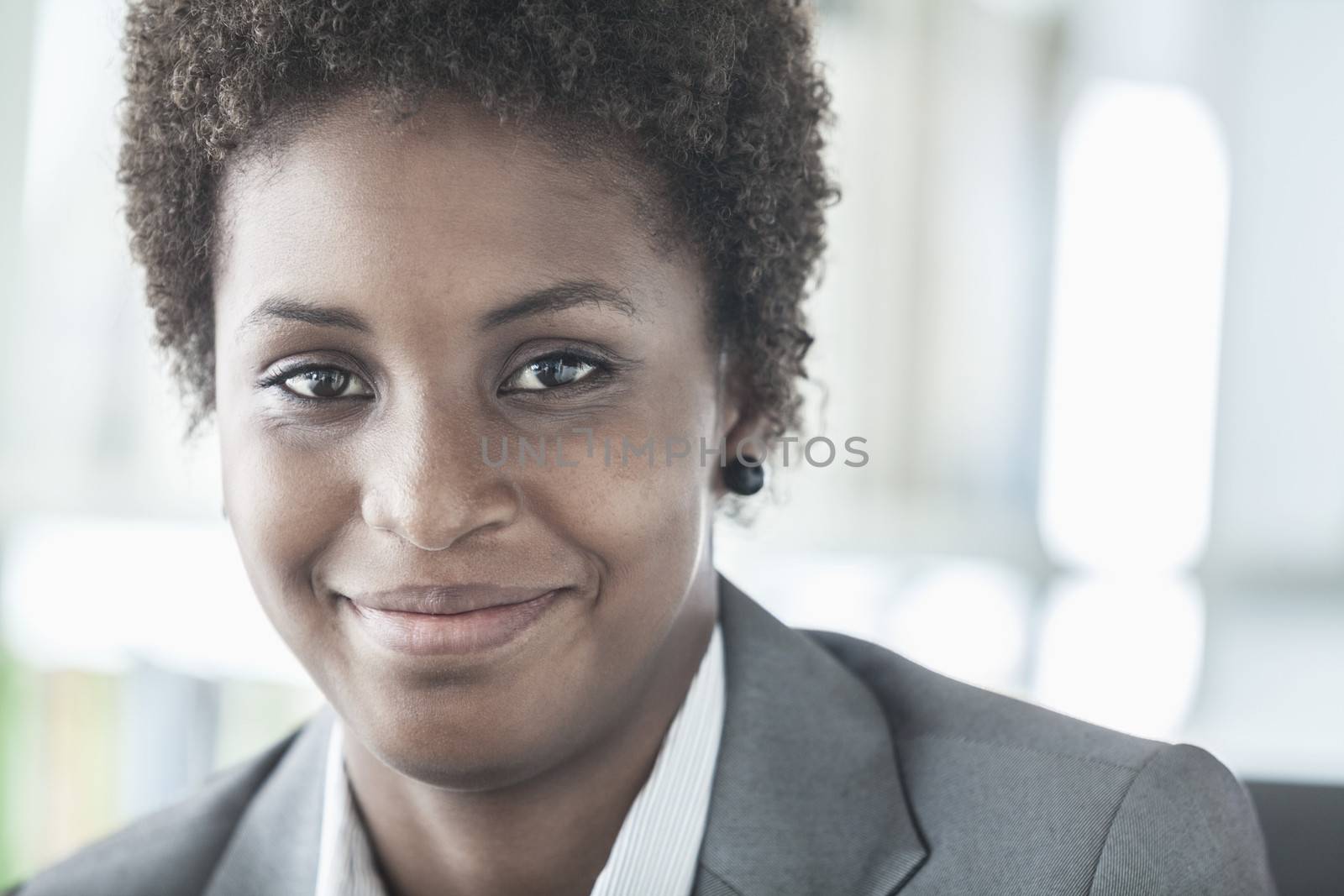 Portrait of smiling young businesswoman with short hair looking at the camera, head and shoulders