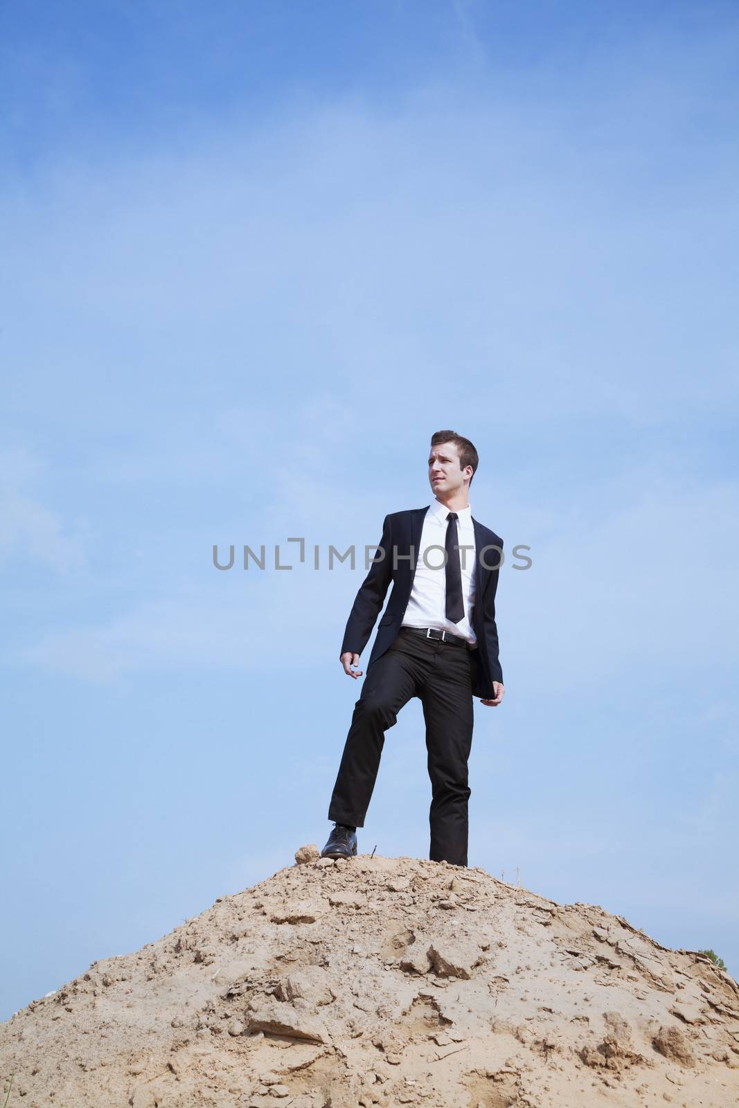 Young solitary businessman standing on a hill in the desert by XiXinXing