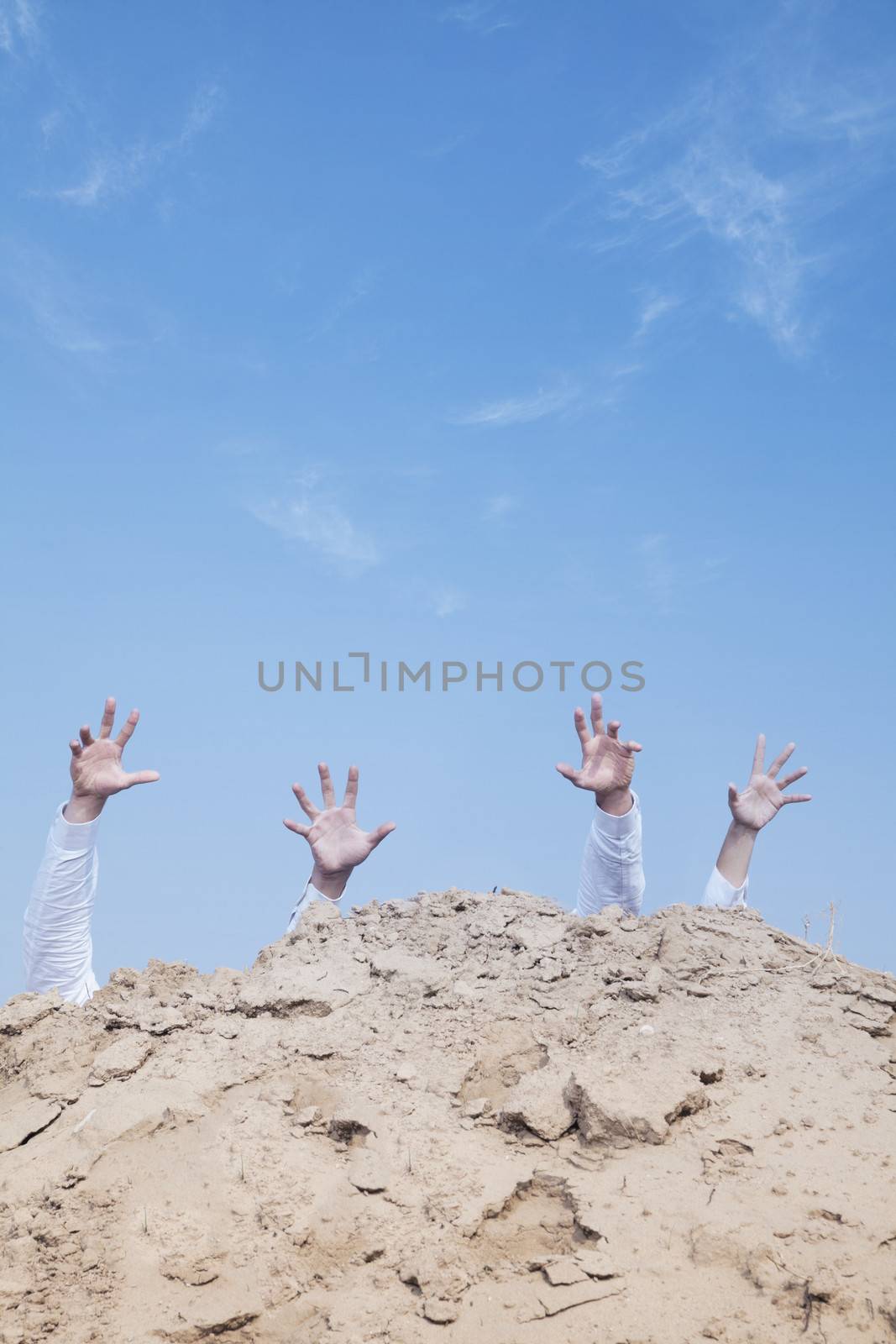 Close-up of hands of businessmen behind a hill in the desert, reaching upwards by XiXinXing