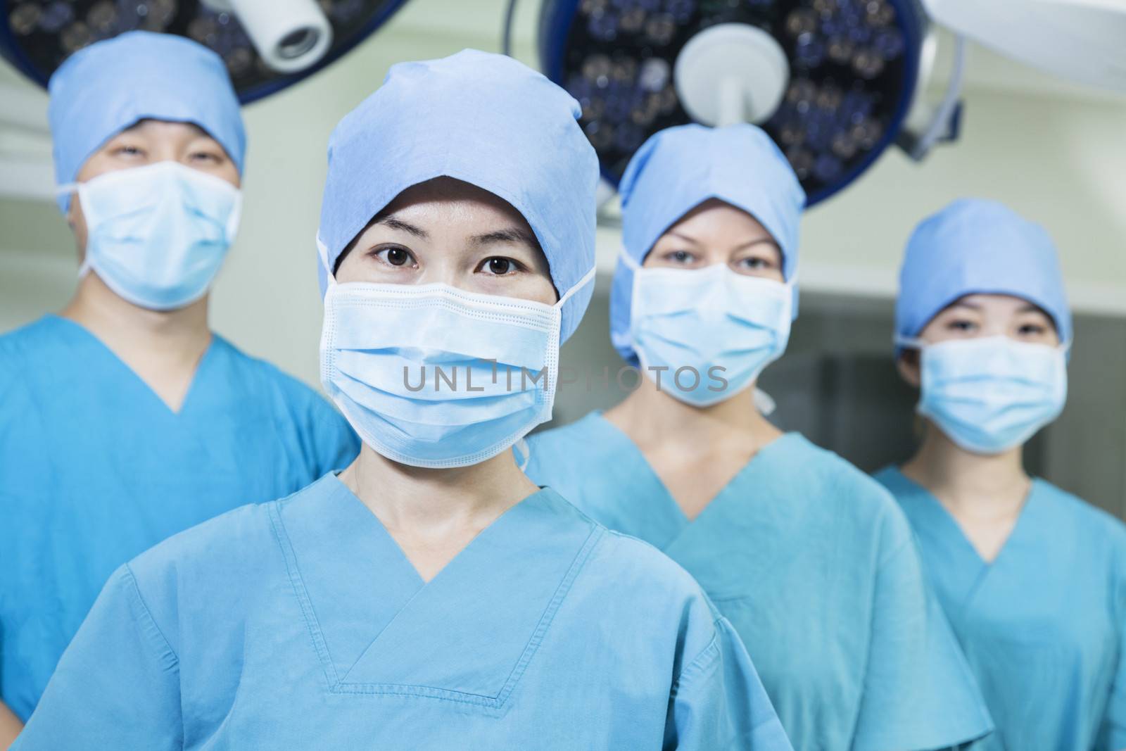 Team of surgeons wearing surgical masks in the operating room, looking at camera by XiXinXing