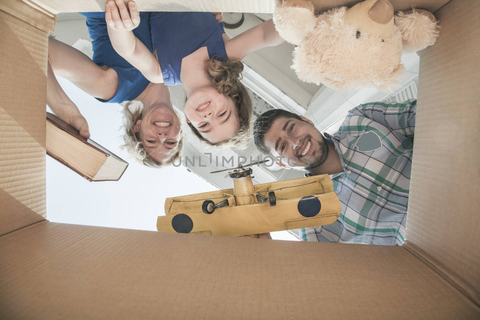 Smiling family looking into a cardboard box, view from directly under