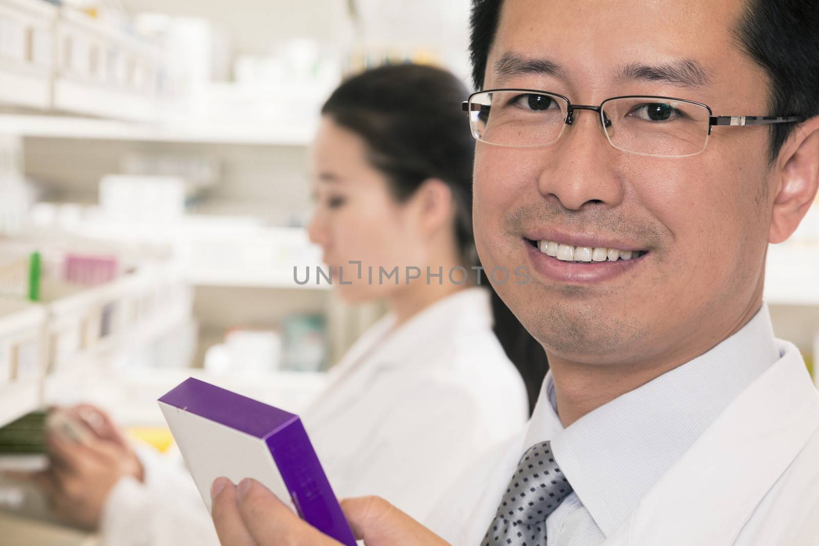 Portrait of smiling pharmacist holding prescription medication and looking at camera