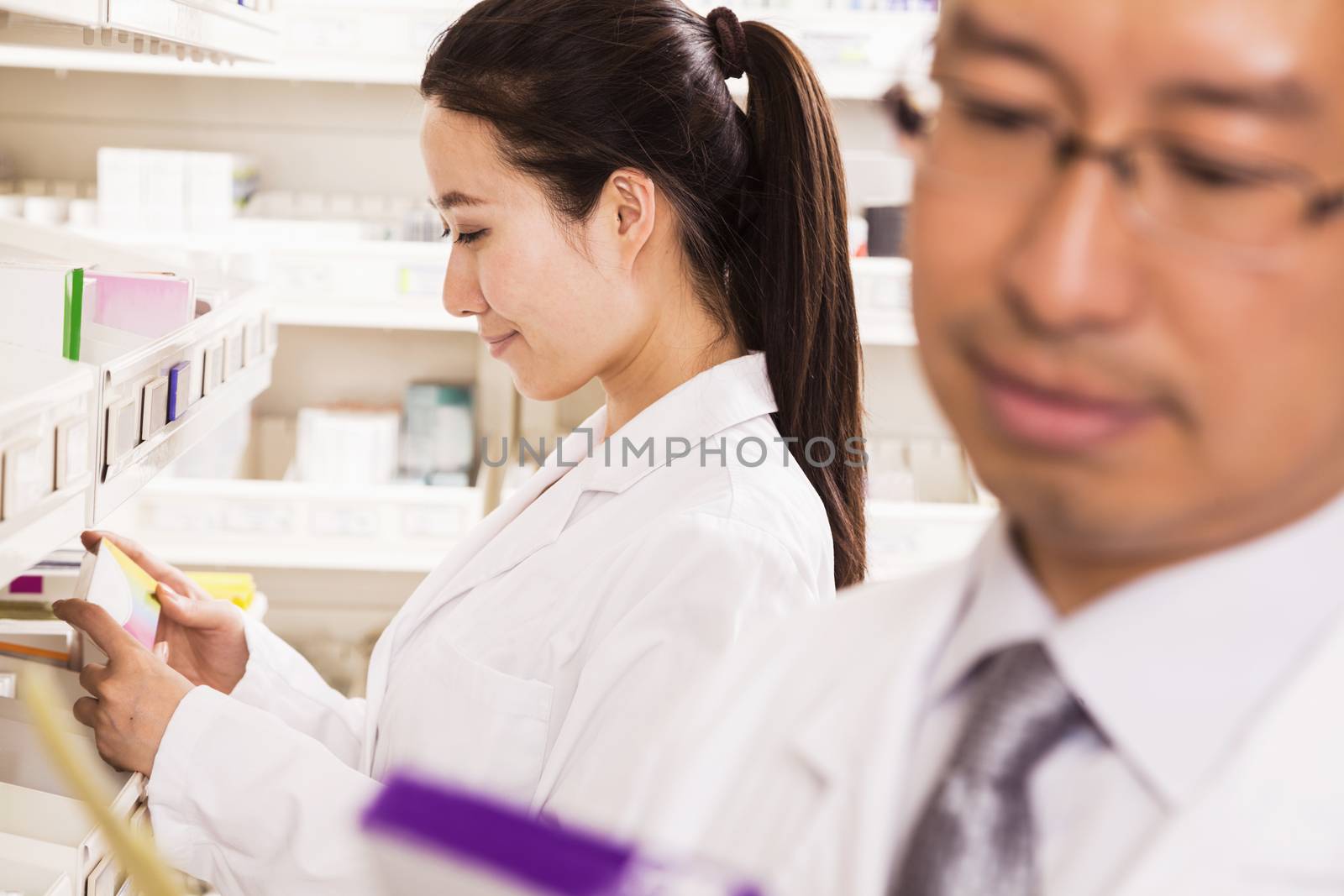 Pharmacist taking down and examining prescription medication in a pharmacy by XiXinXing