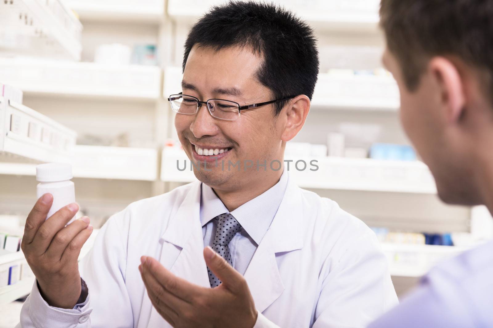 Smiling pharmacist showing prescription medication to a customer