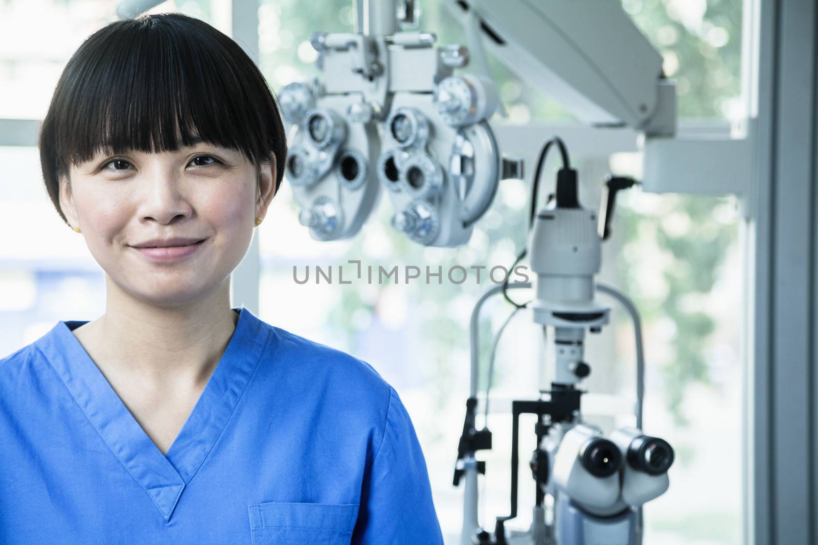 Portrait of smiling female optometrist with eye test equipment