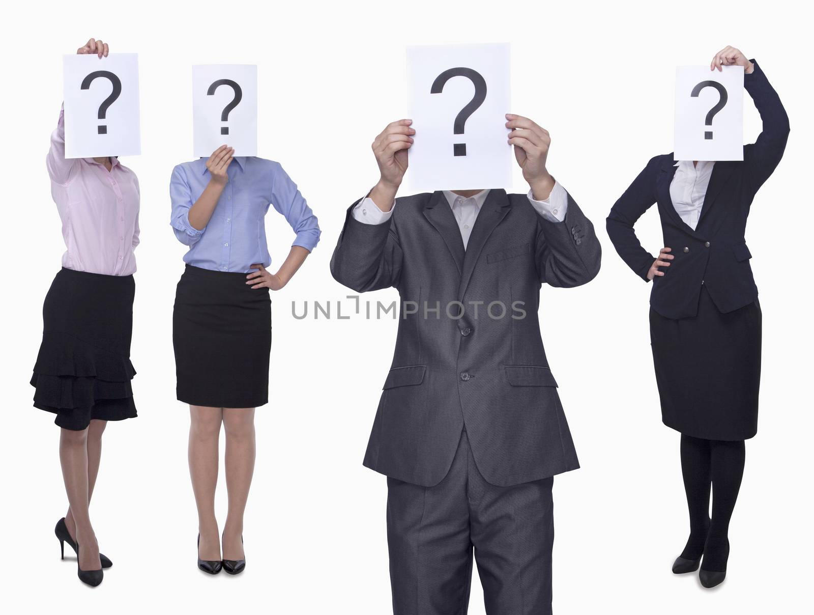 Four business people holding up paper with question mark, obscured face, studio shot by XiXinXing