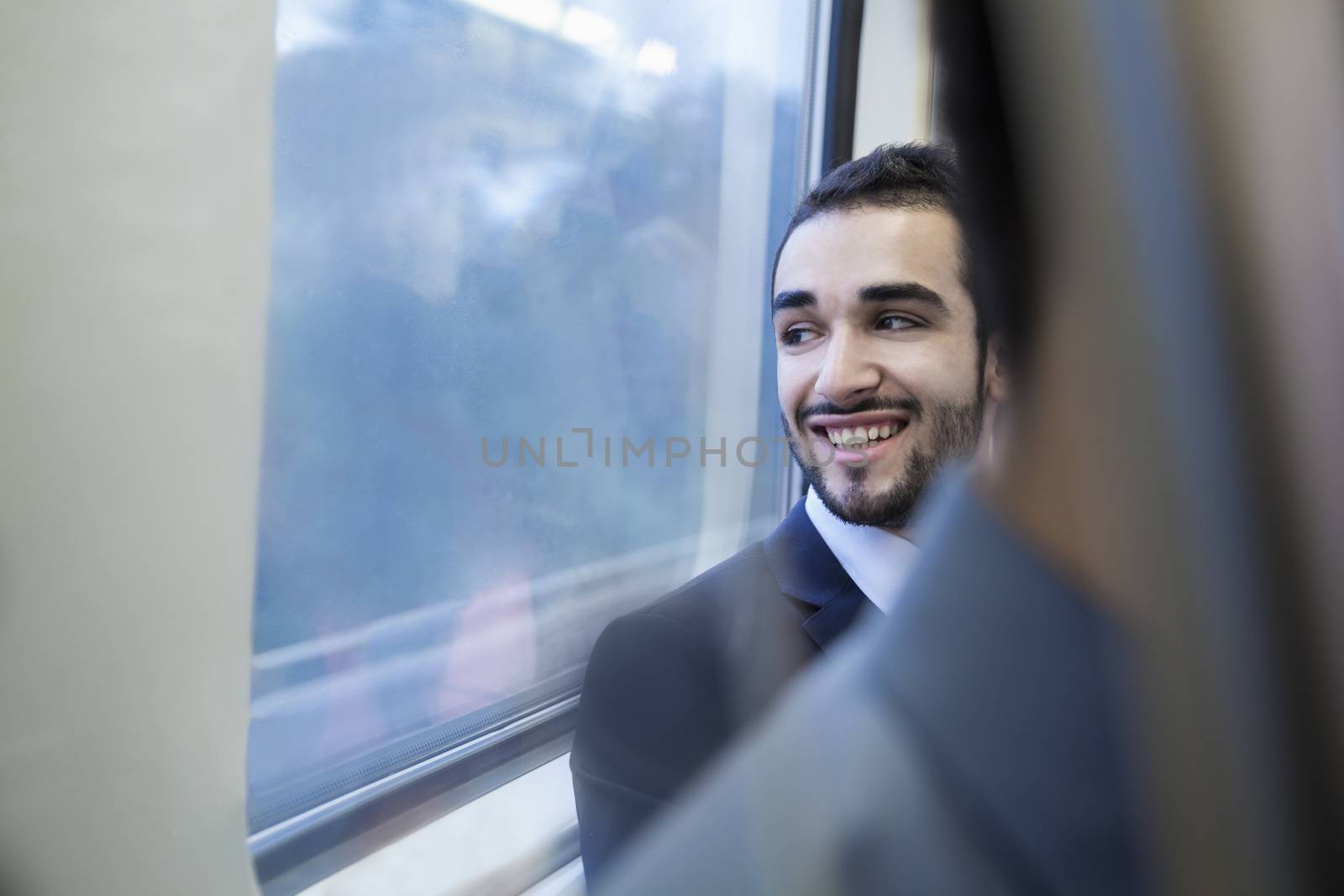Young businessman smiling and looking out the window of the subway