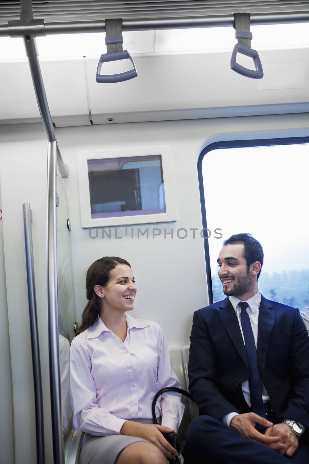 Two young business people sitting and chatting on the subway by XiXinXing