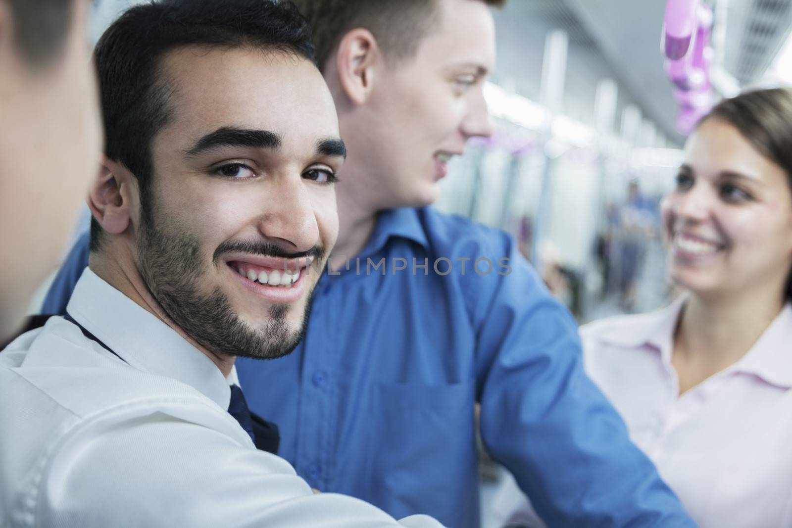 Portrait of young smiling businessman standing on the subway, looking at camera 