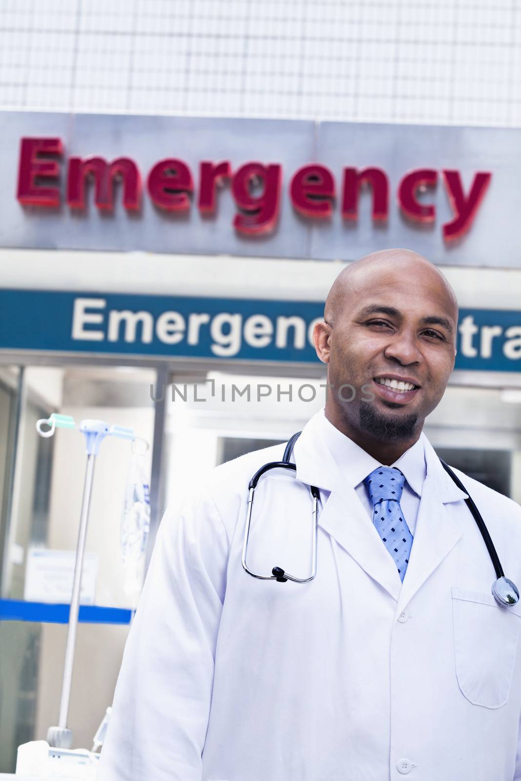 Portrait of smiling doctor outside of the hospital, emergency room sign in the background