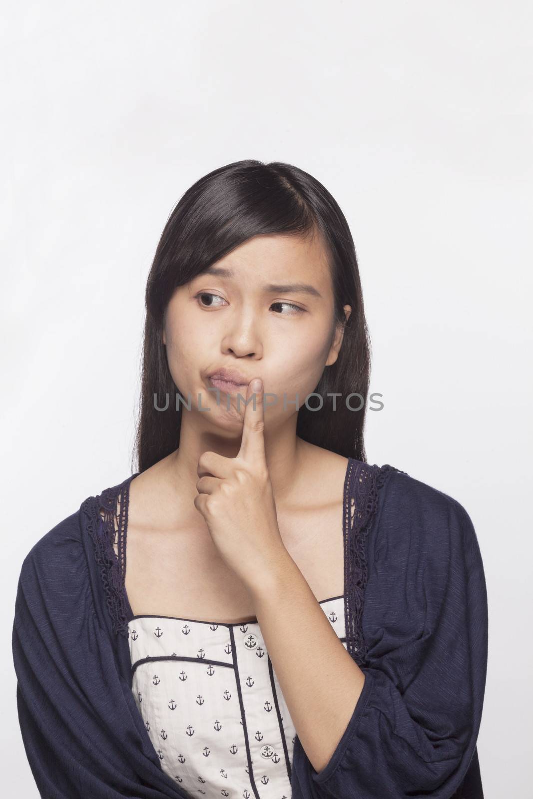 Young woman with finger to her mouth contemplating, studio shot by XiXinXing