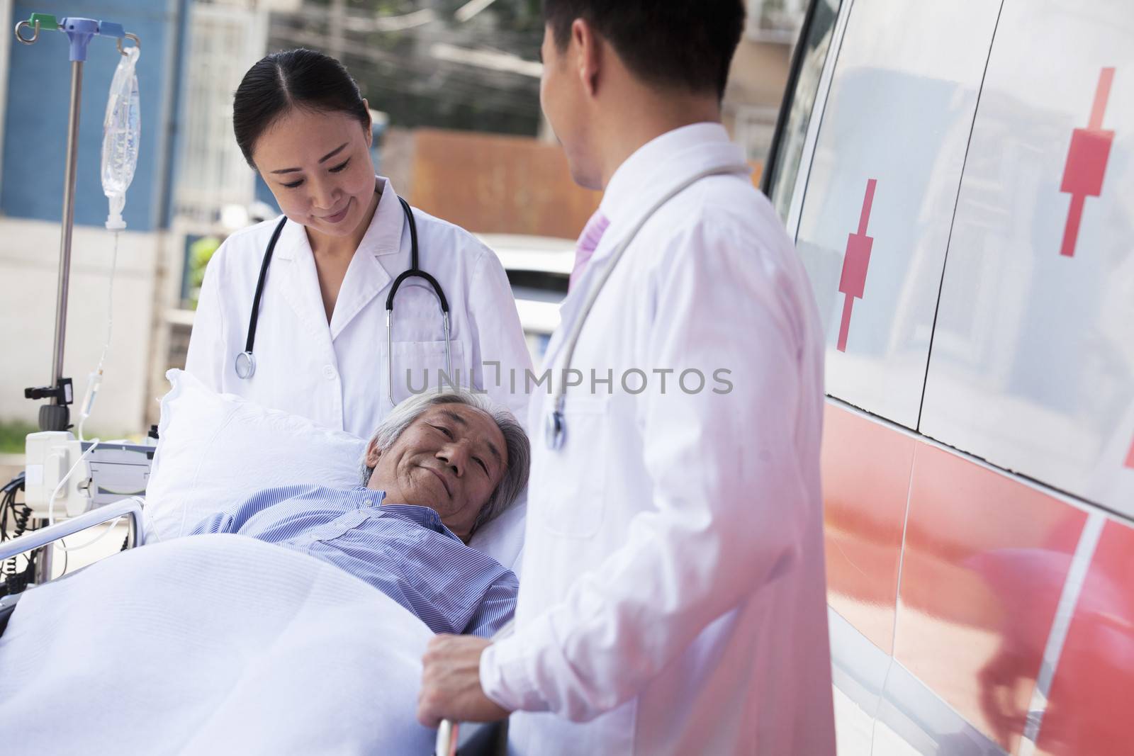 Two doctors wheeling in a elderly patient on a stretcher in front of an ambulance by XiXinXing