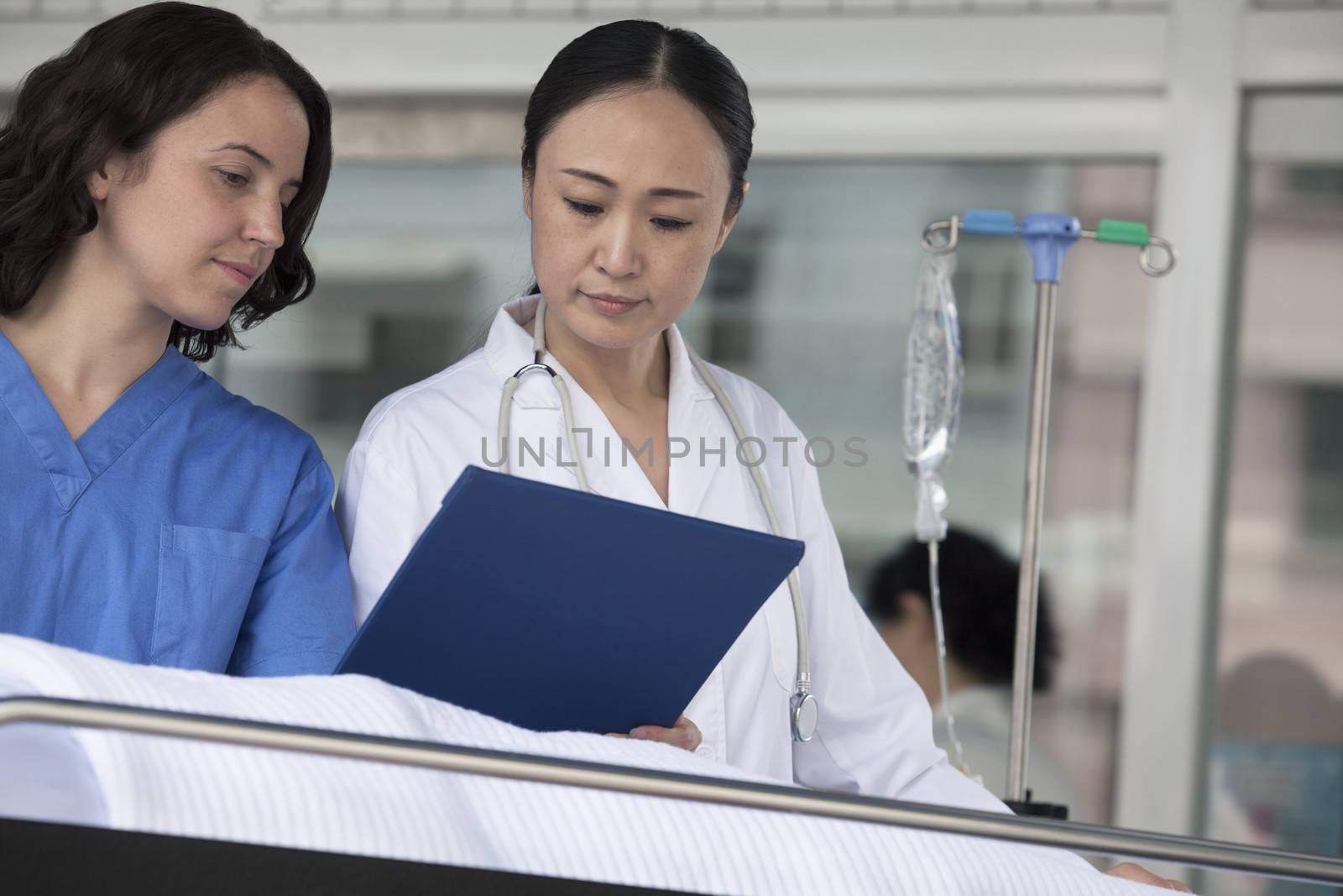 Paramedic and doctor looking down at the medical record of patient on a stretcher in front of the hospital