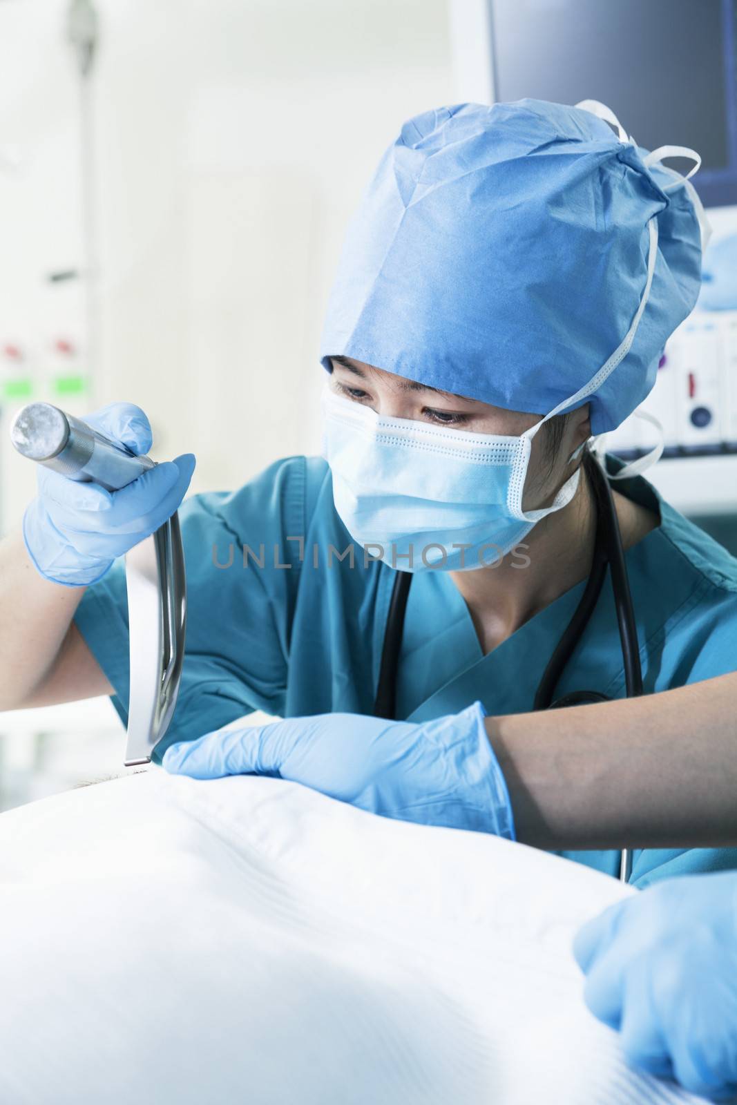Surgeon looking down and holding surgical equipment in the operating room, close-up