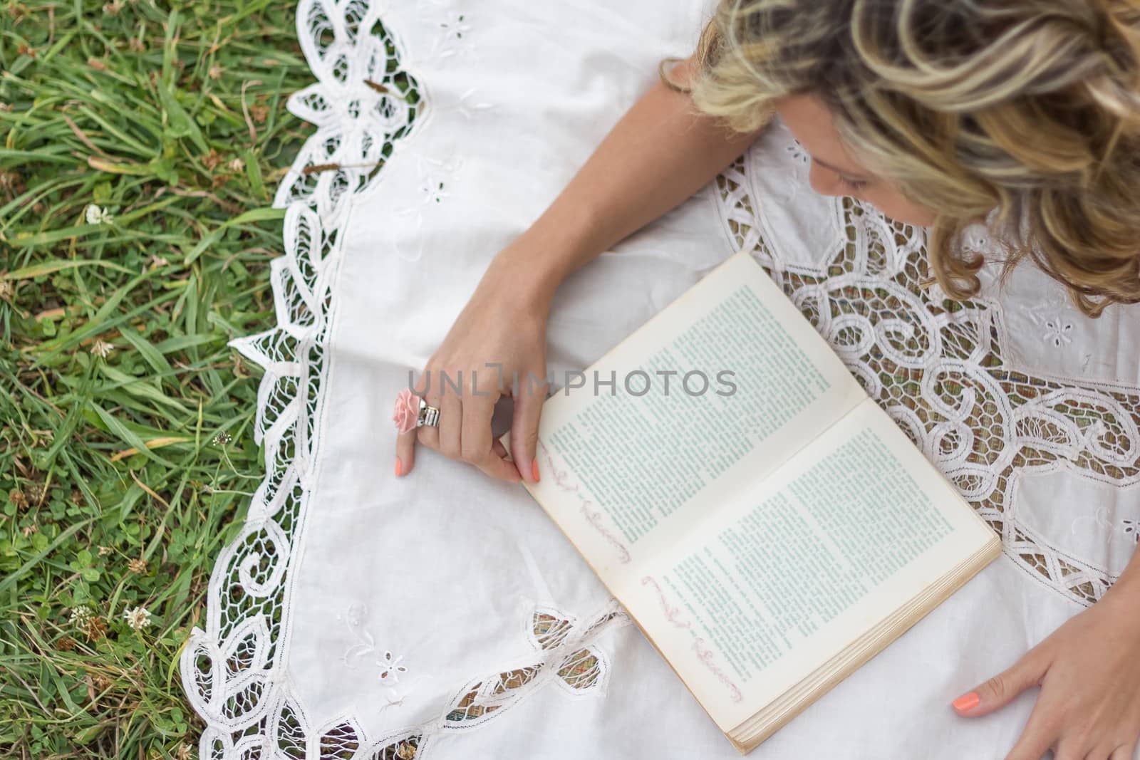 Beautiful young girl with book lying on the grass