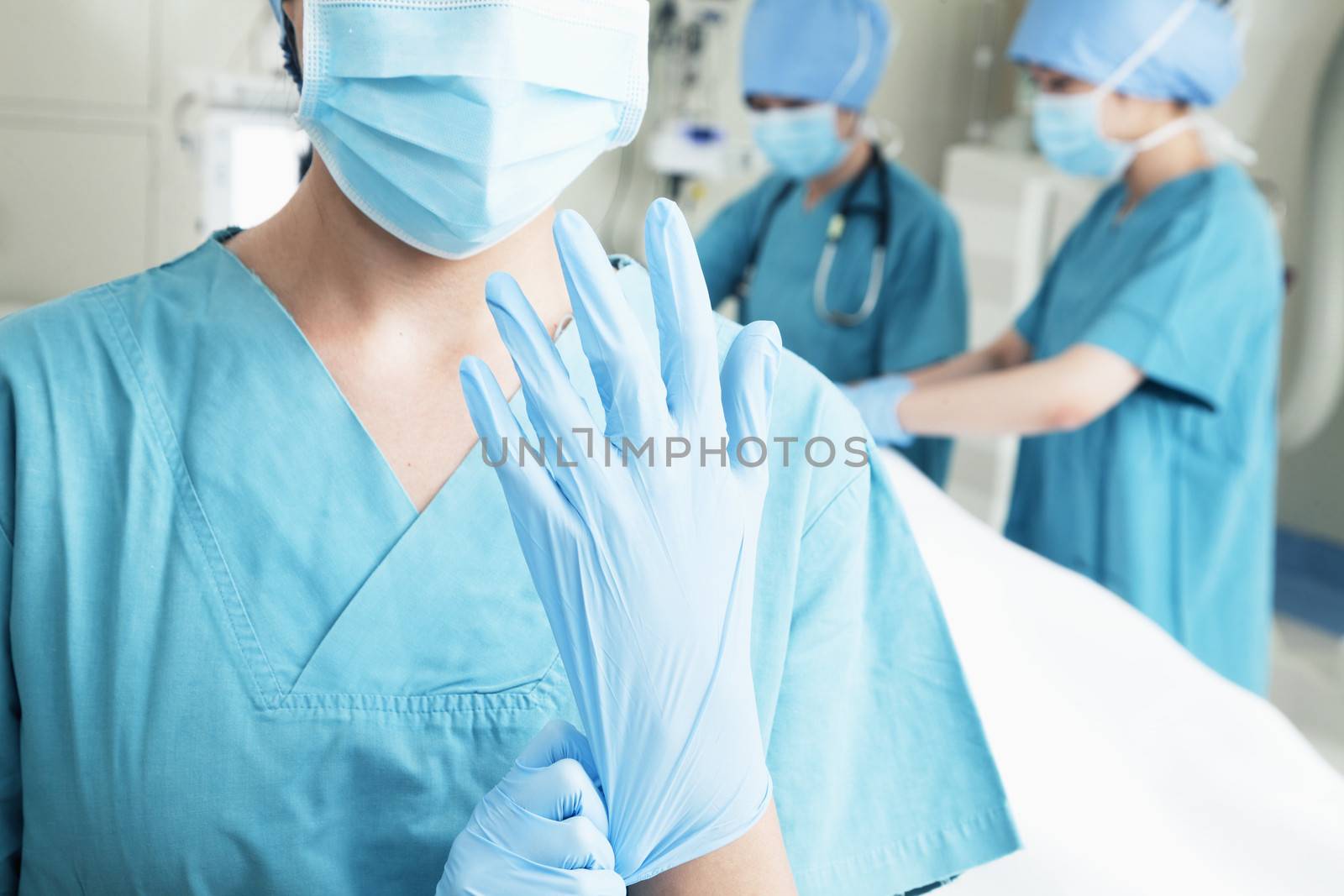 Female surgeon putting on gloves in the operating room, midsection by XiXinXing