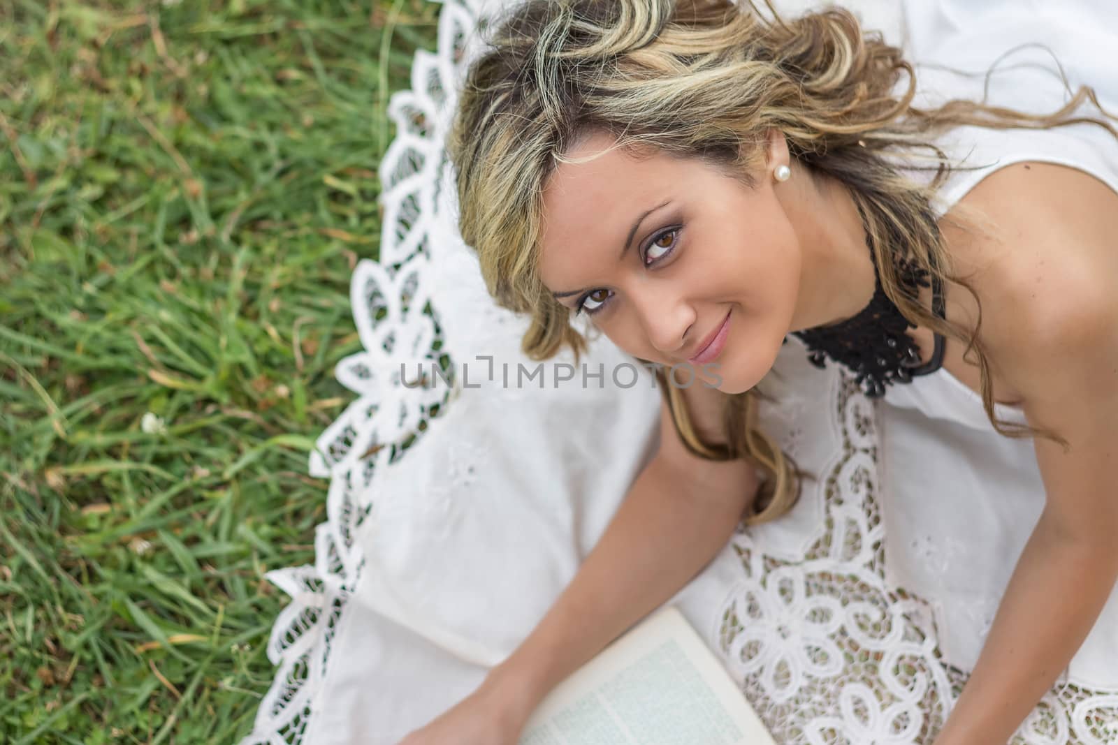 Beautiful young girl with book lying on the grass