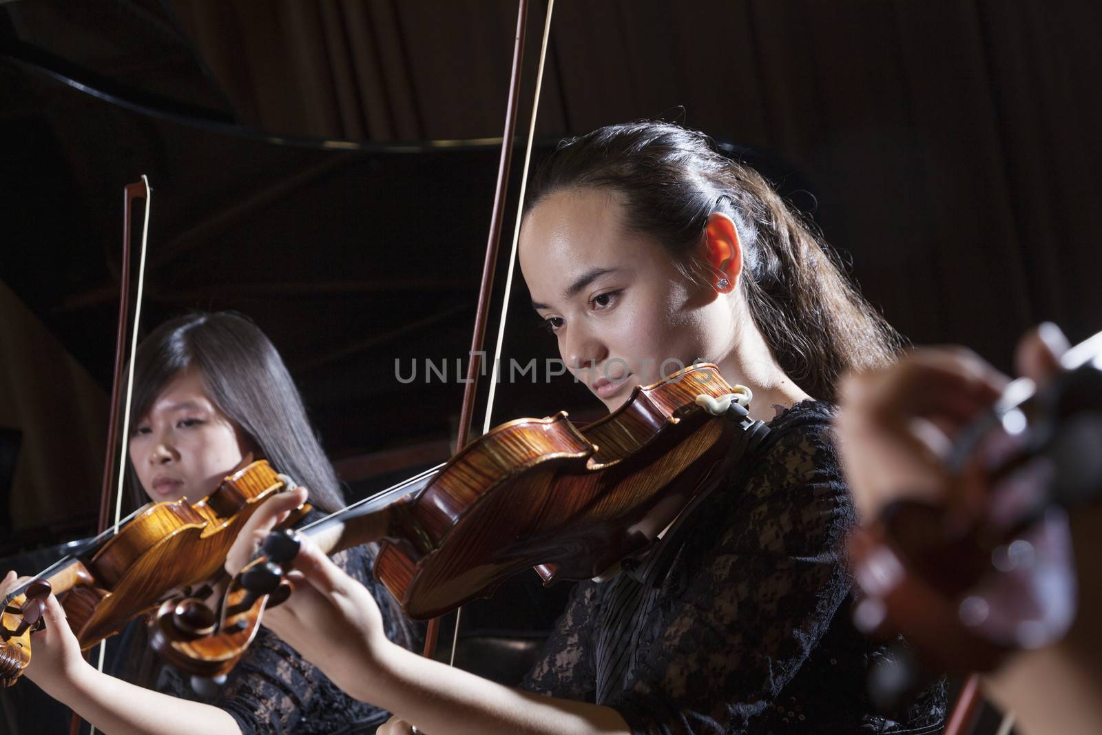 Violinists playing during a performance, head and shoulders