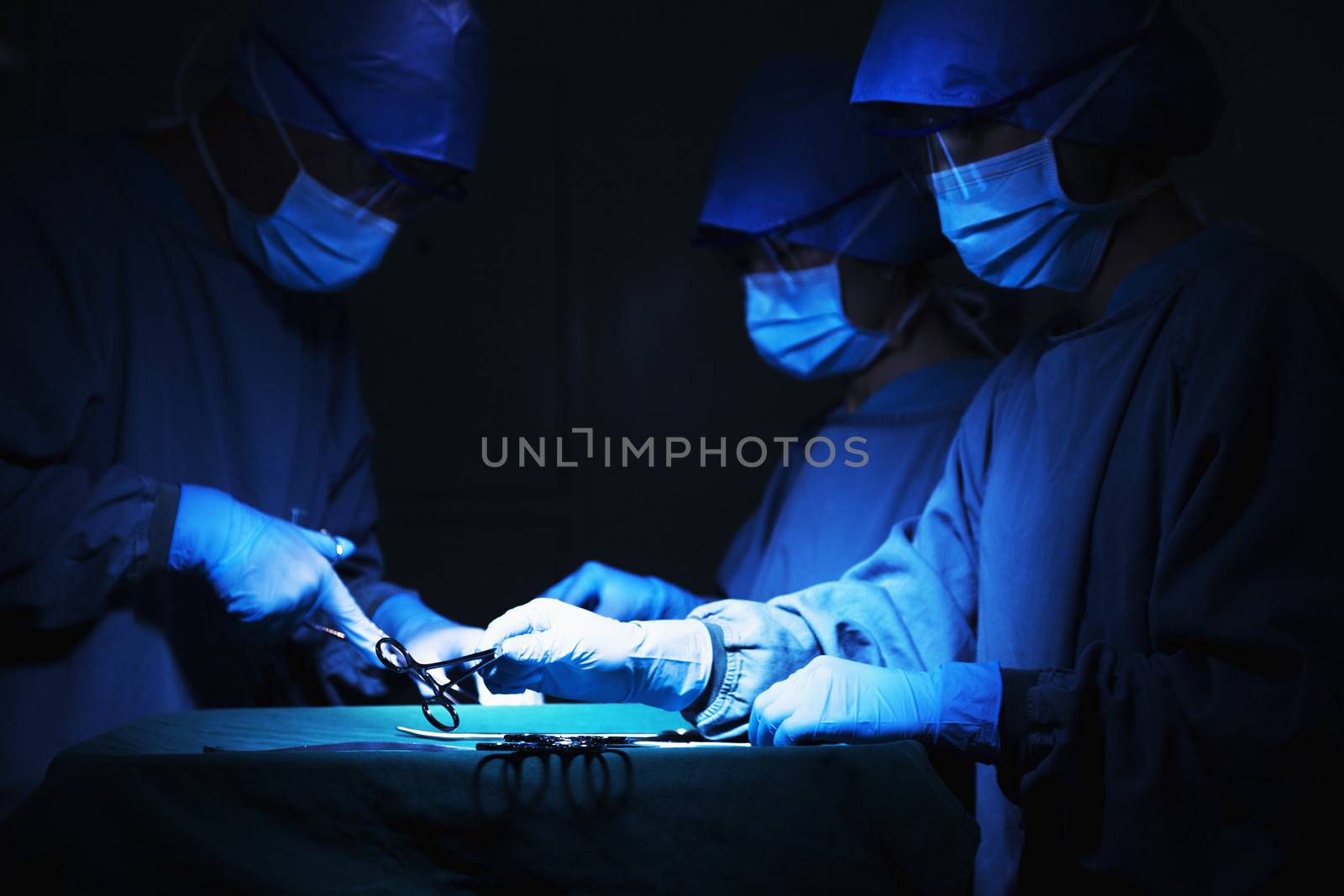 Team of surgeons holding surgical equipment at the operating table and working