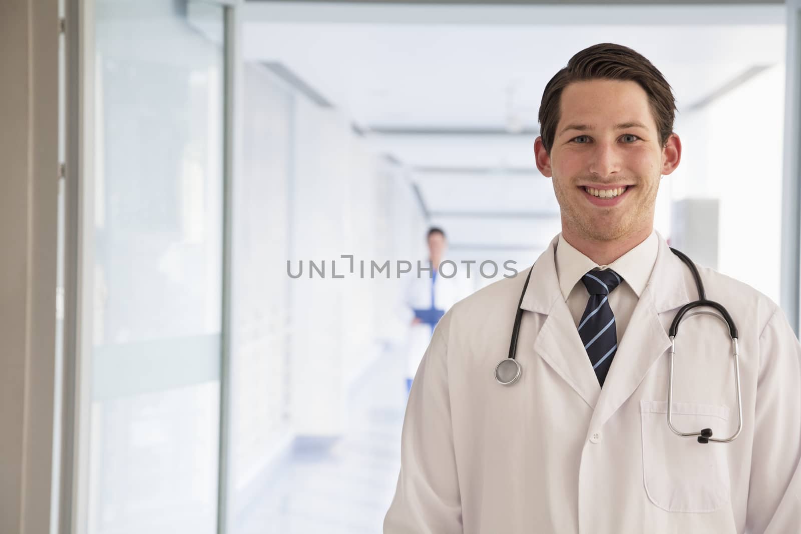 Portrait of young doctor in lab coat in the hospital, looking at camera