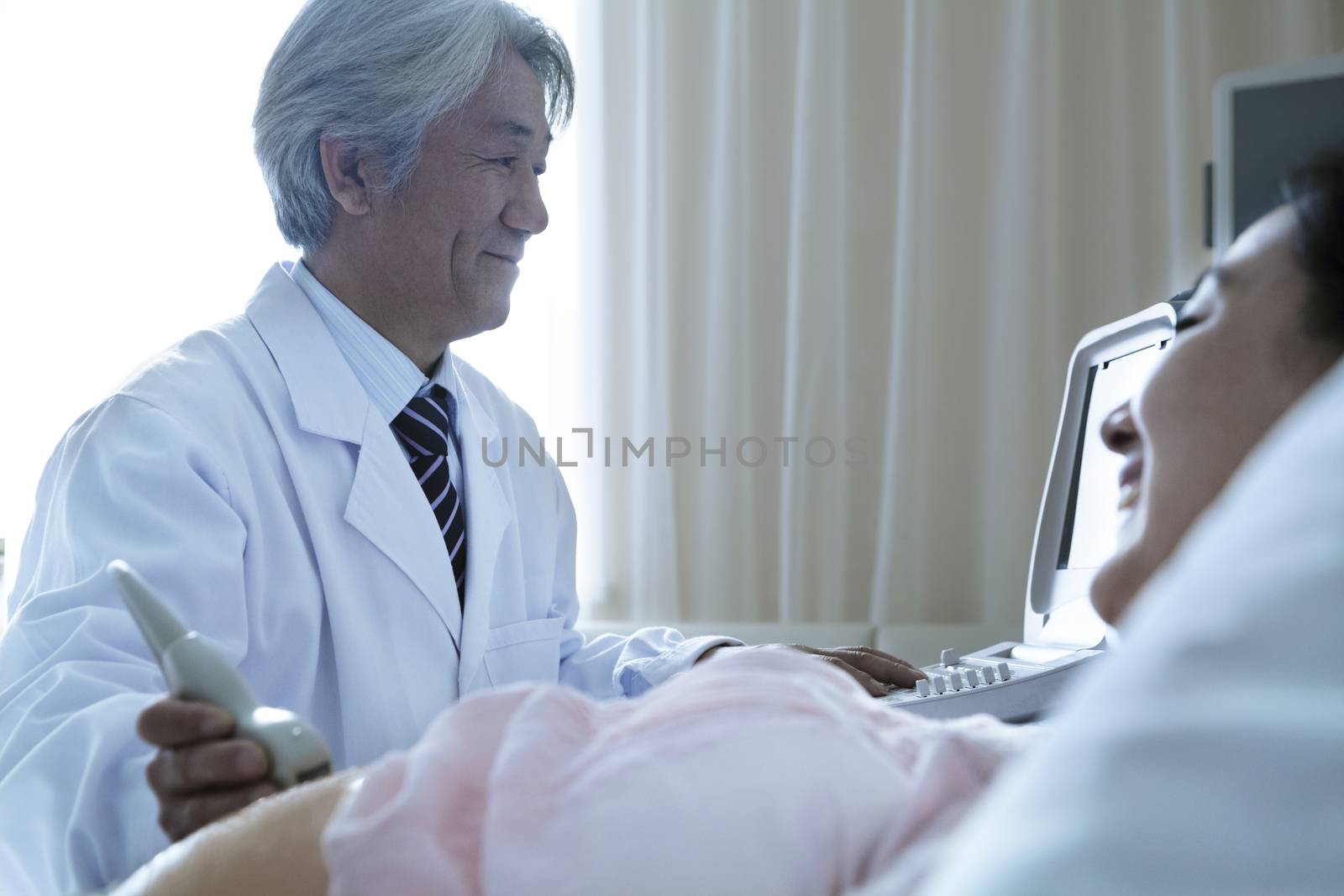 Doctor doing an ultrasound on a pregnant woman lying on her back in the hospital