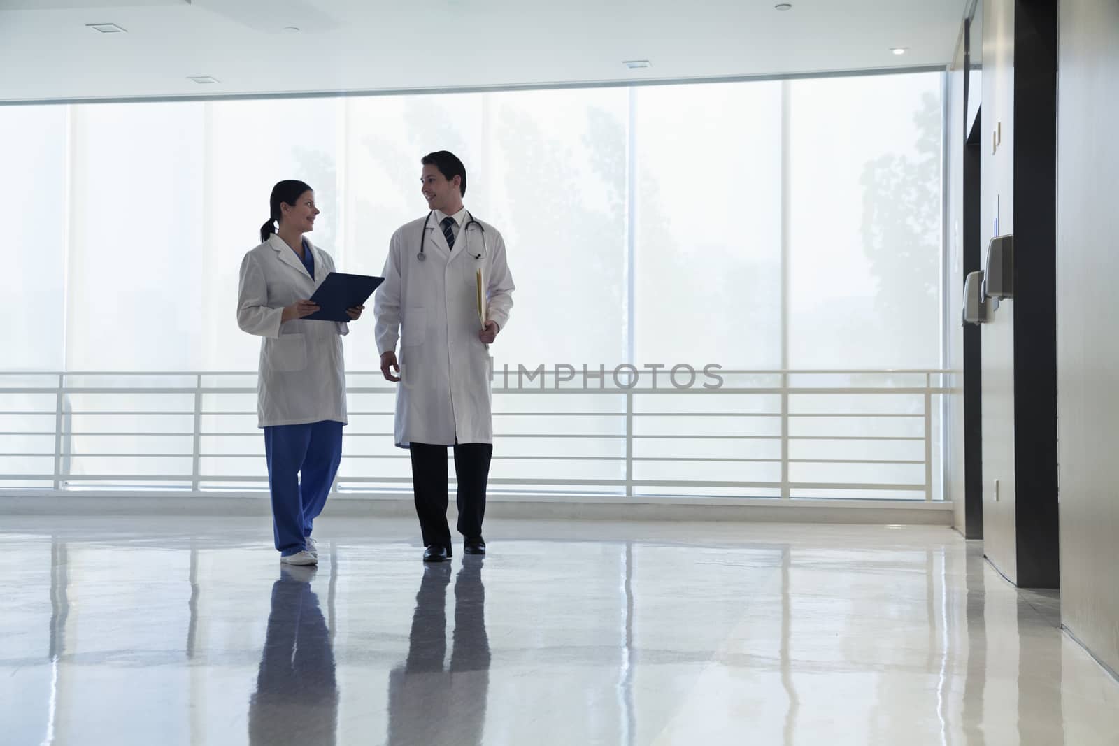 Two doctors walking and smiling in the hospital, full length