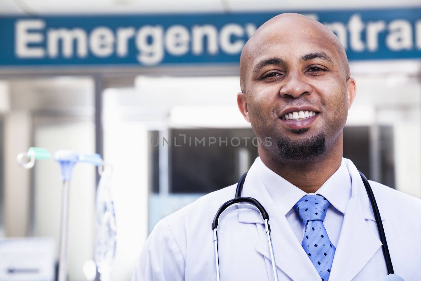 Portrait of smiling doctor outside of the hospital, emergency room sign in the background