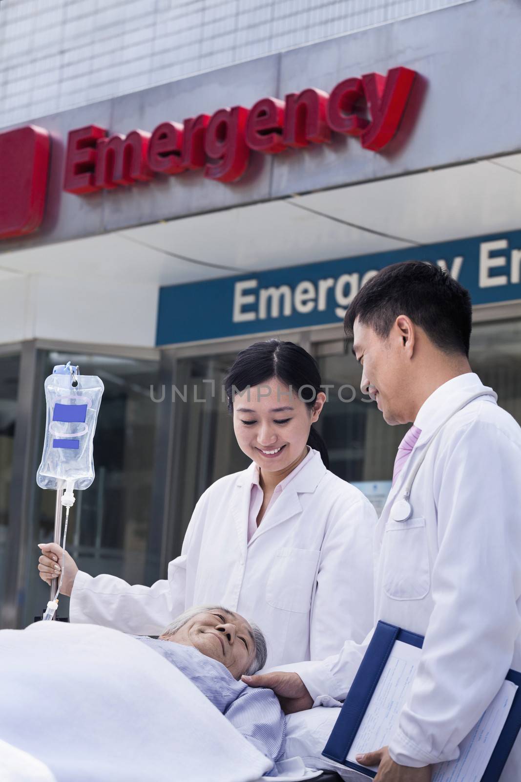 Two doctors wheeling in a patient on a stretcher in front of the emergency room