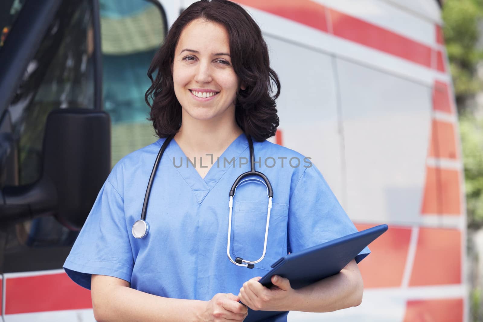 Portrait of smiling female paramedic in front of am ambulance by XiXinXing