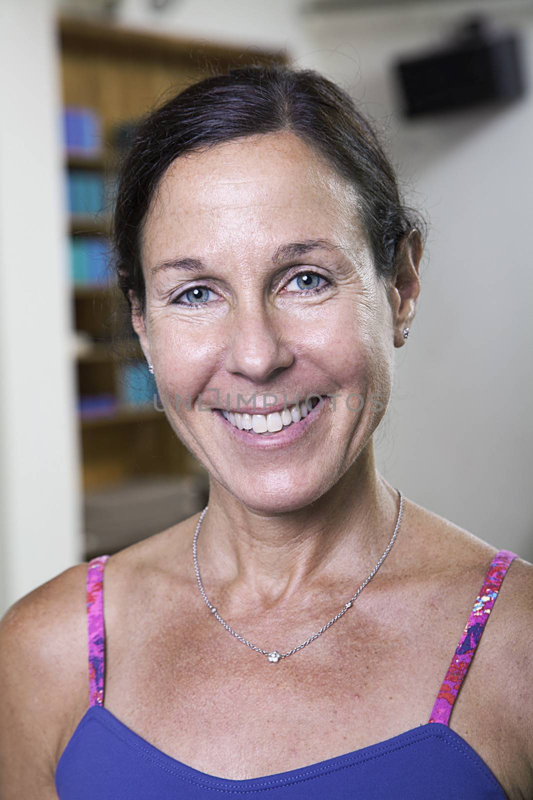 Portrait of smiling woman in a yoga studio, head and shoulders