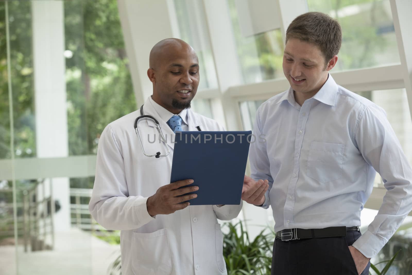 Doctor and patient looking down and discussing medical record in the hospital