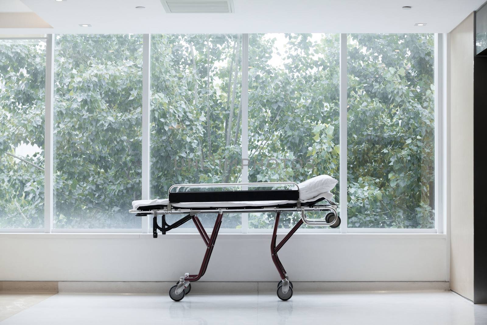 Empty stretcher in a hospital by glass windows, no people by XiXinXing
