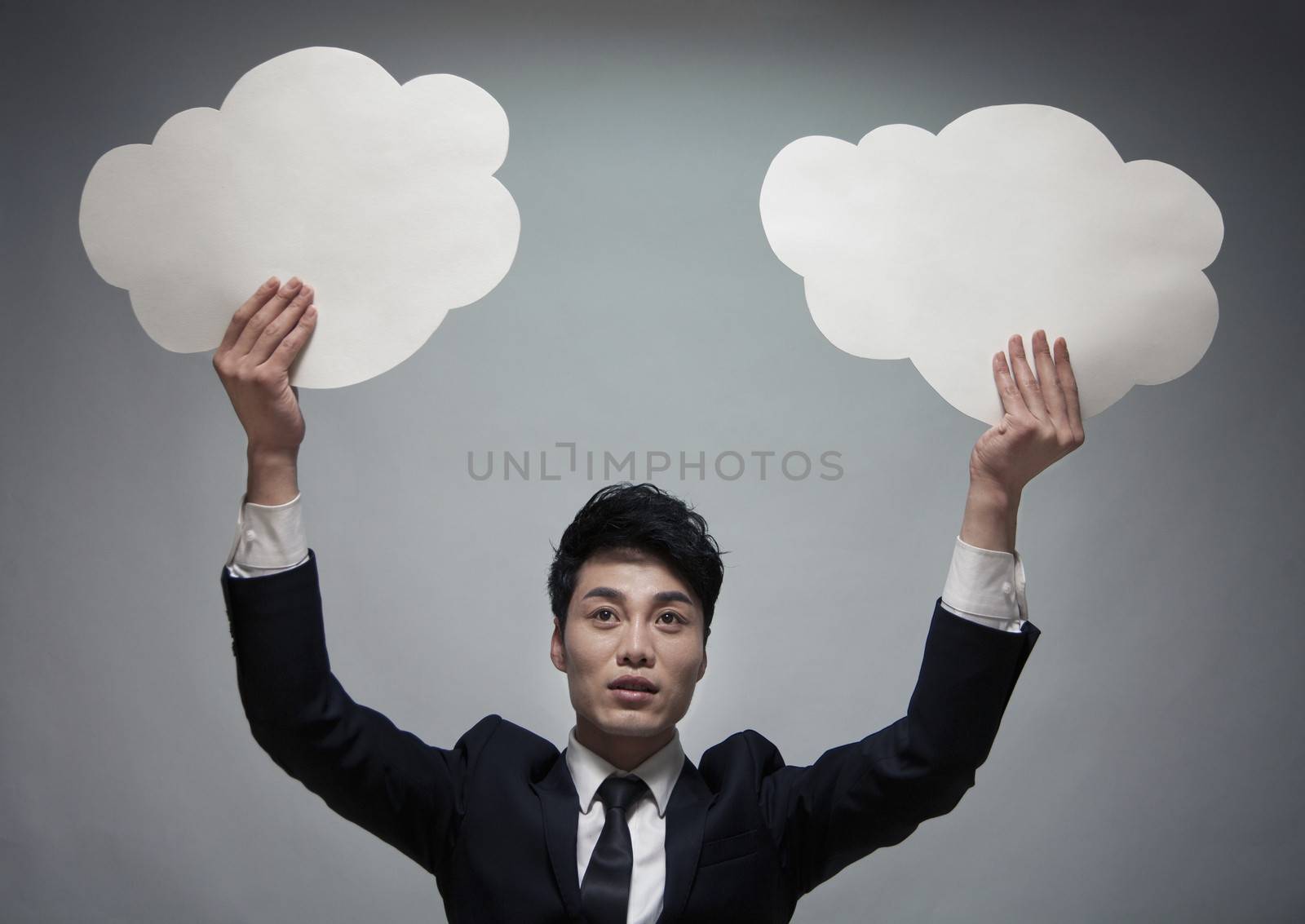 Businessman holding two paper clouds, studio shot