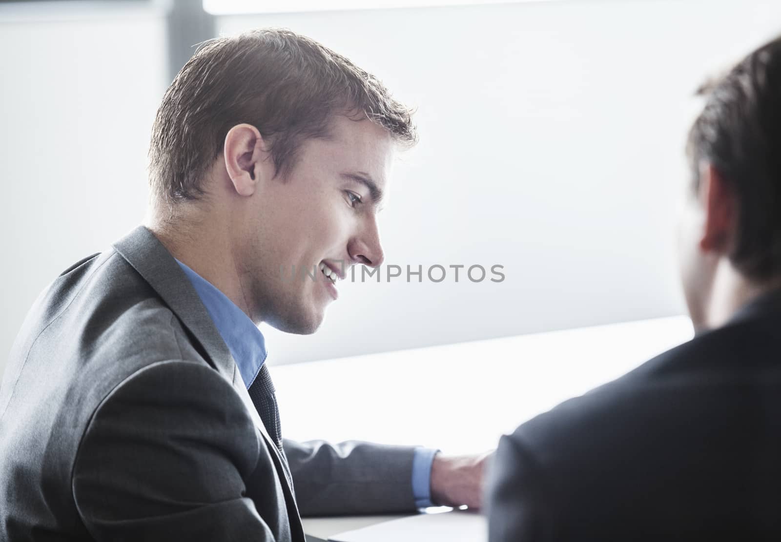 Two business people smiling and looking down at a business meeting
