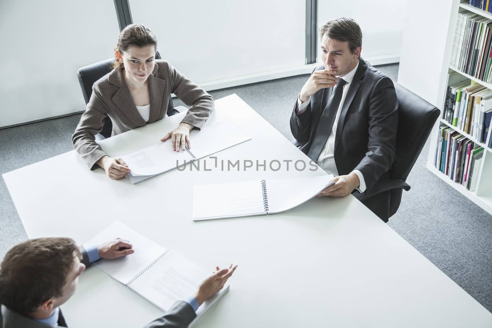 Three business people sitting around a table and having a business meeting, high angle view  by XiXinXing