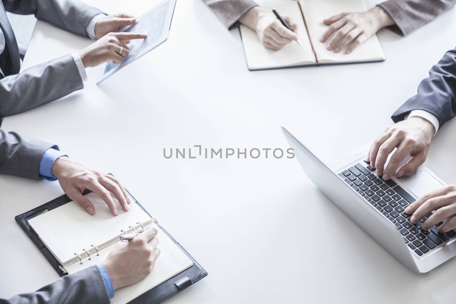 Four business people around a table and during a business meeting, hands only 