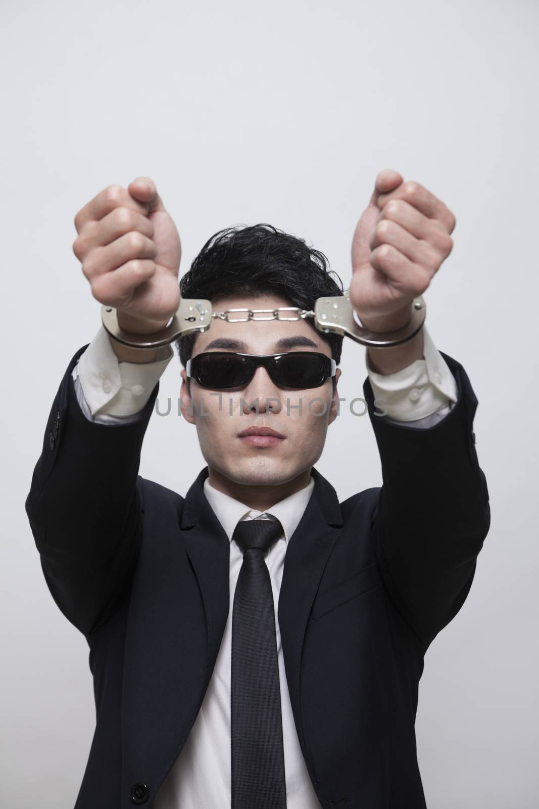 Cool businessman with sunglasses in handcuffs, studio shot