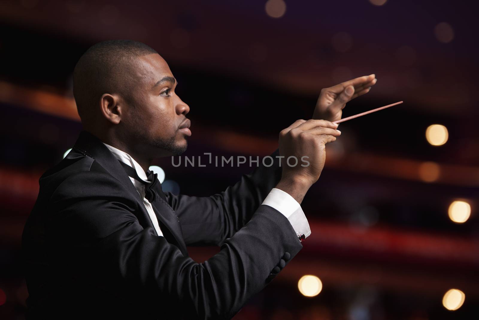 Young conductor with baton raised at a performance 