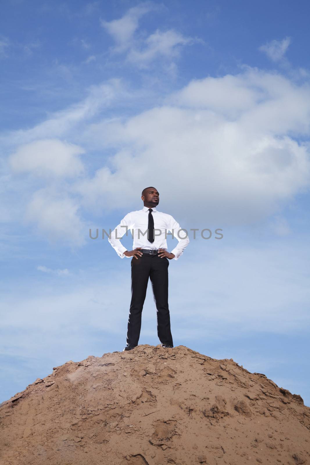 Young businessman with hands on hips in the desert