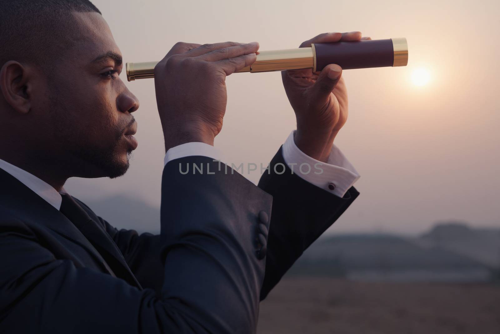 Young businessman looking through telescope in  the middle of the desert
