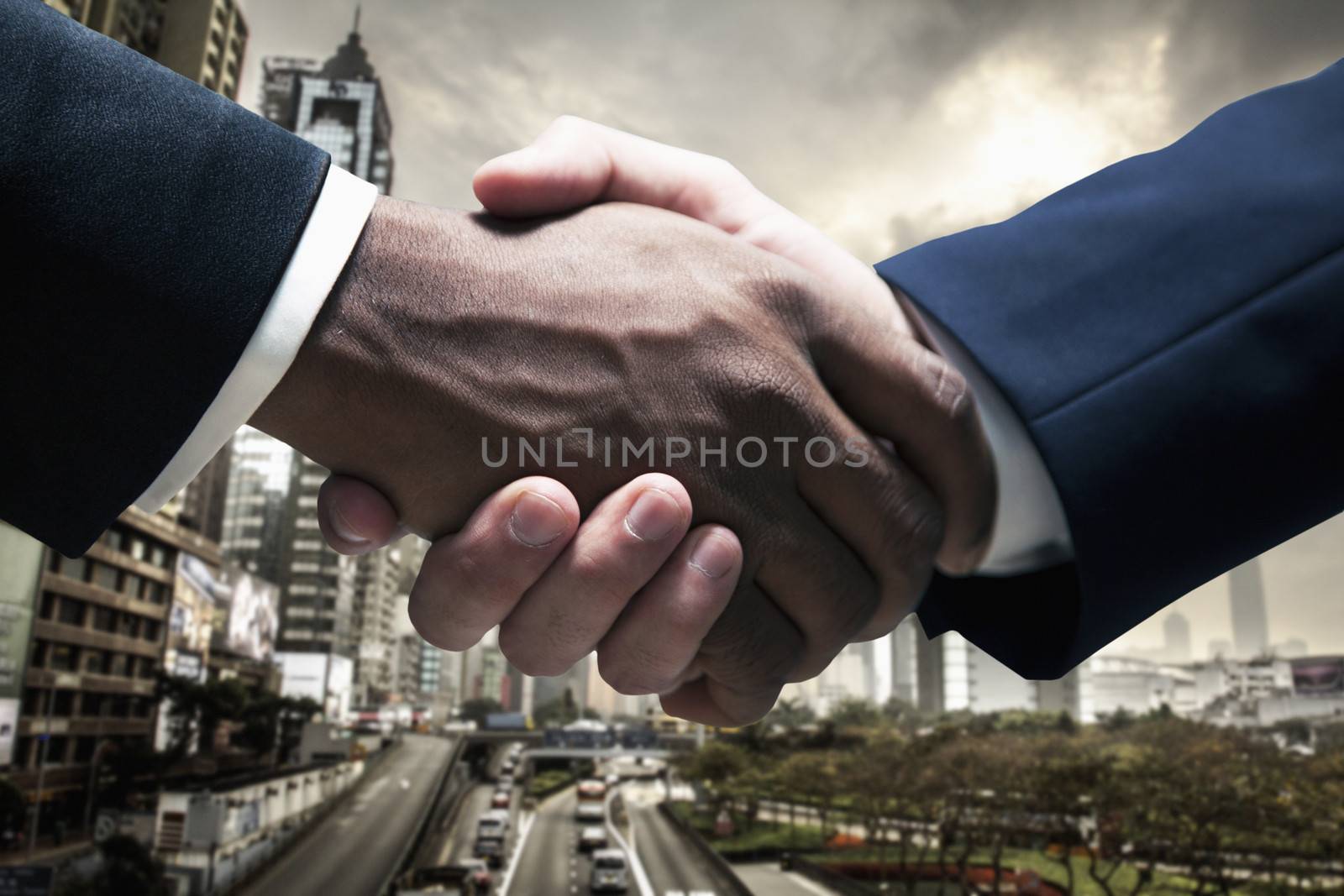 Close up of businessmen shaking hands with cityscape in the background by XiXinXing