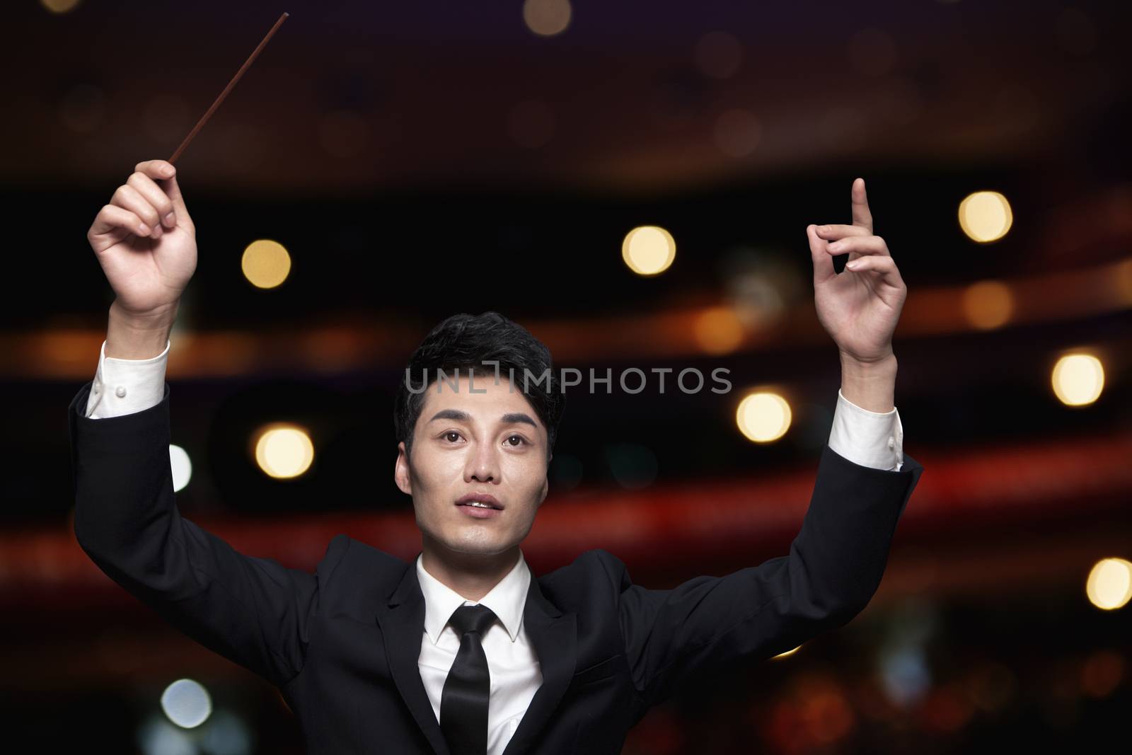 Young conductor with baton raised at a performance 