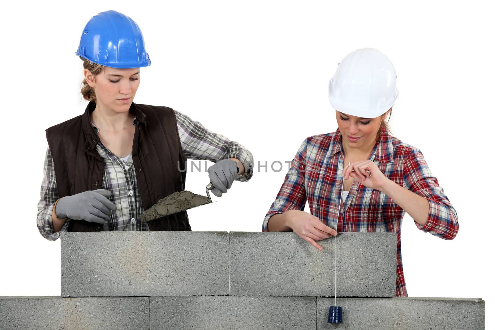 Two female mason working on a wall. by phovoir