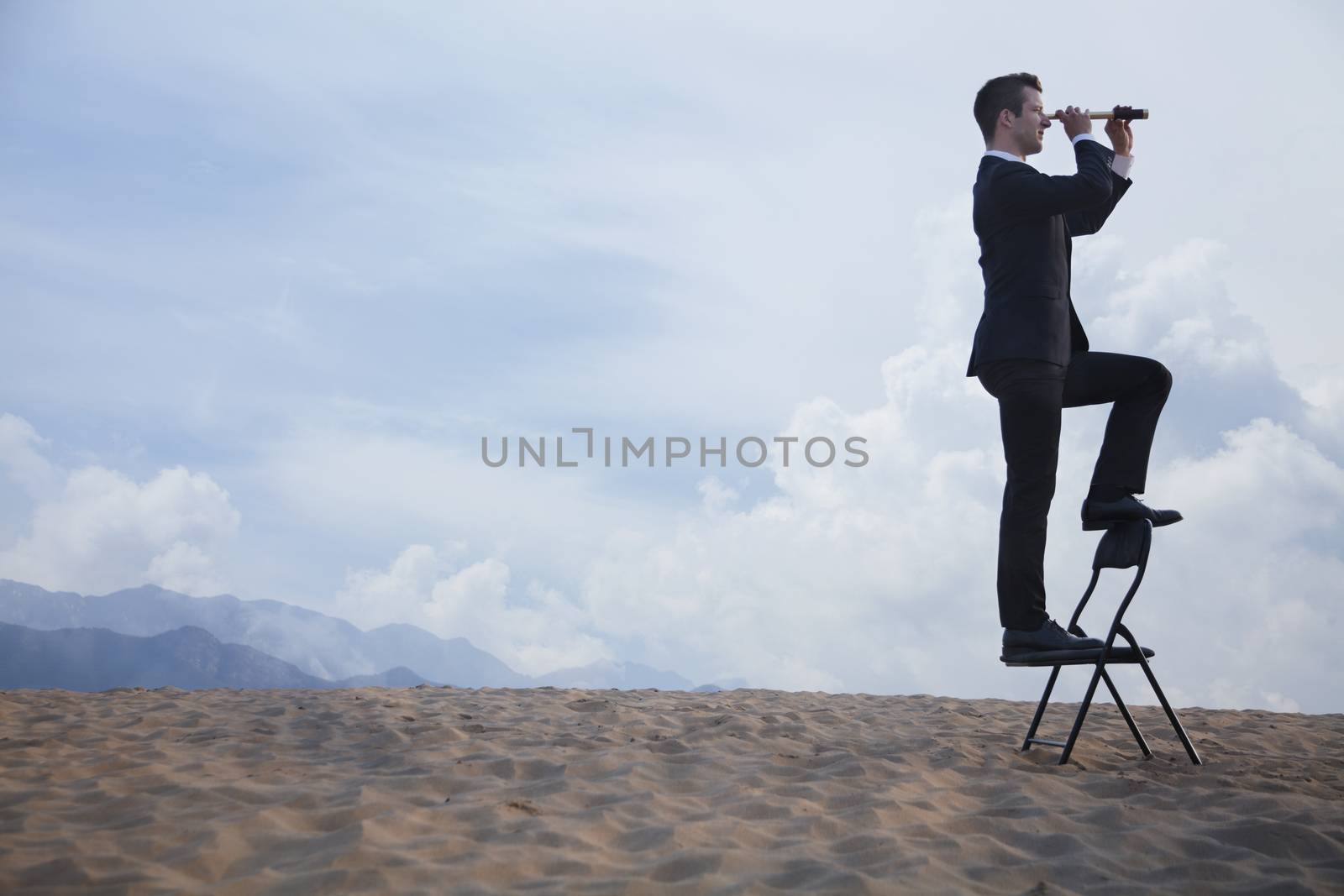 Businessman standing on a chair and looking through a telescope in the middle of the desert  by XiXinXing