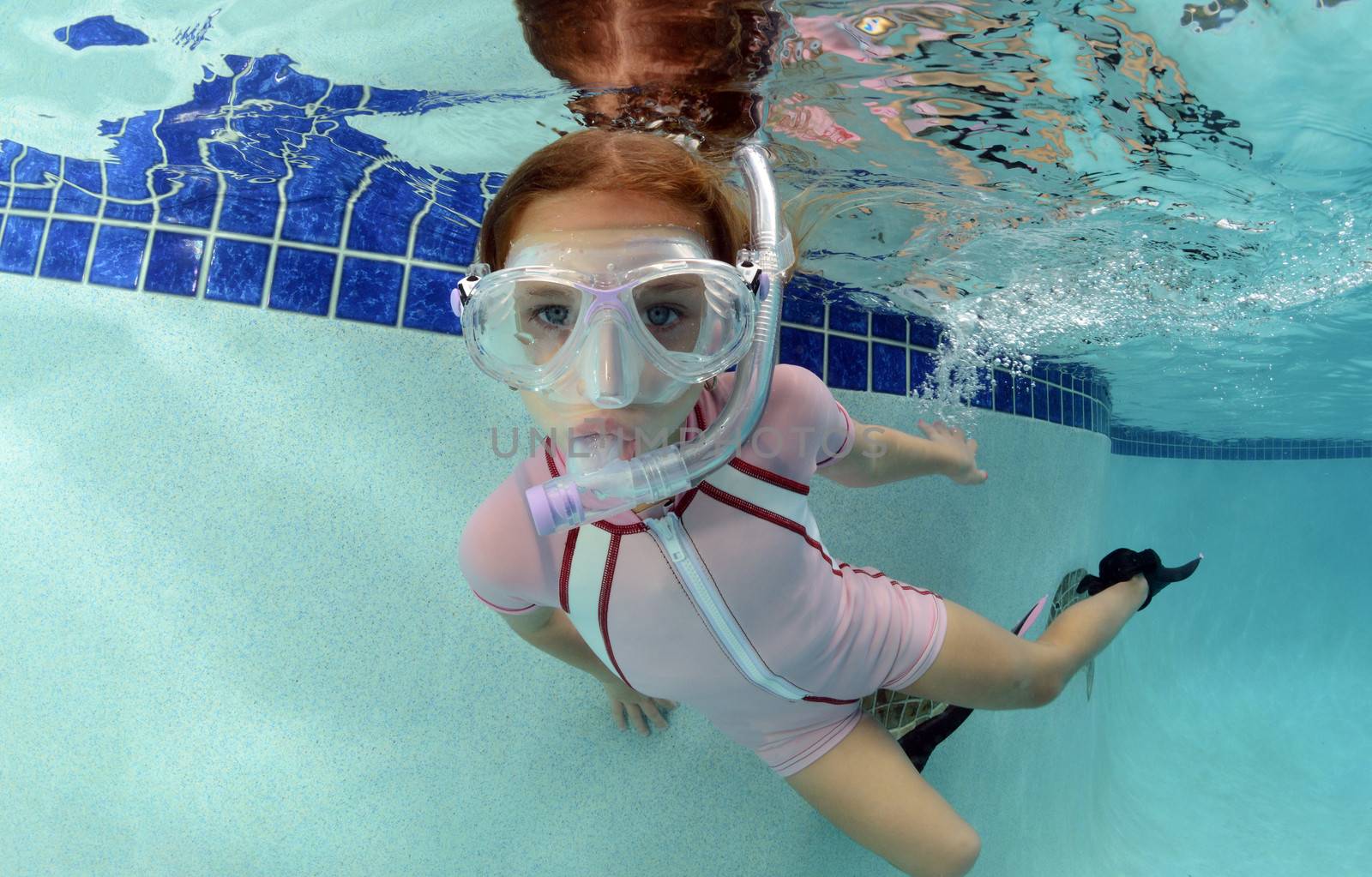 young child swimming with goggles and snorkel