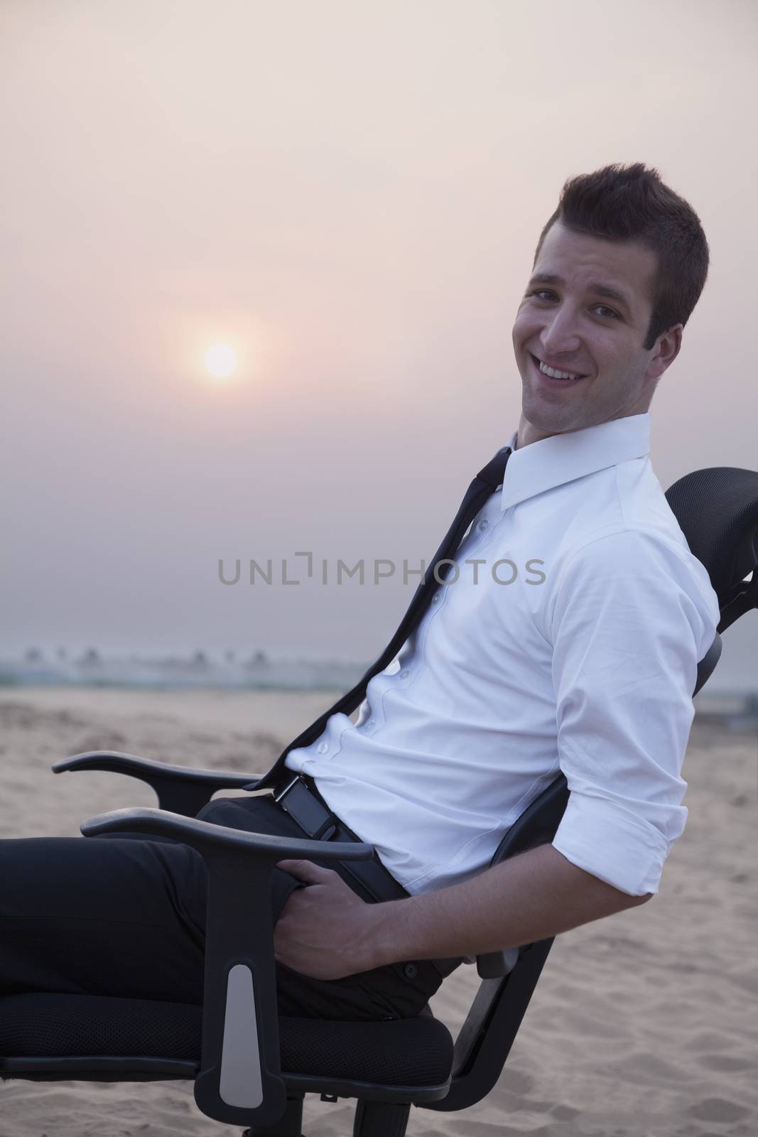 Businessman sitting on a chair and looking at camera in the middle of the desert