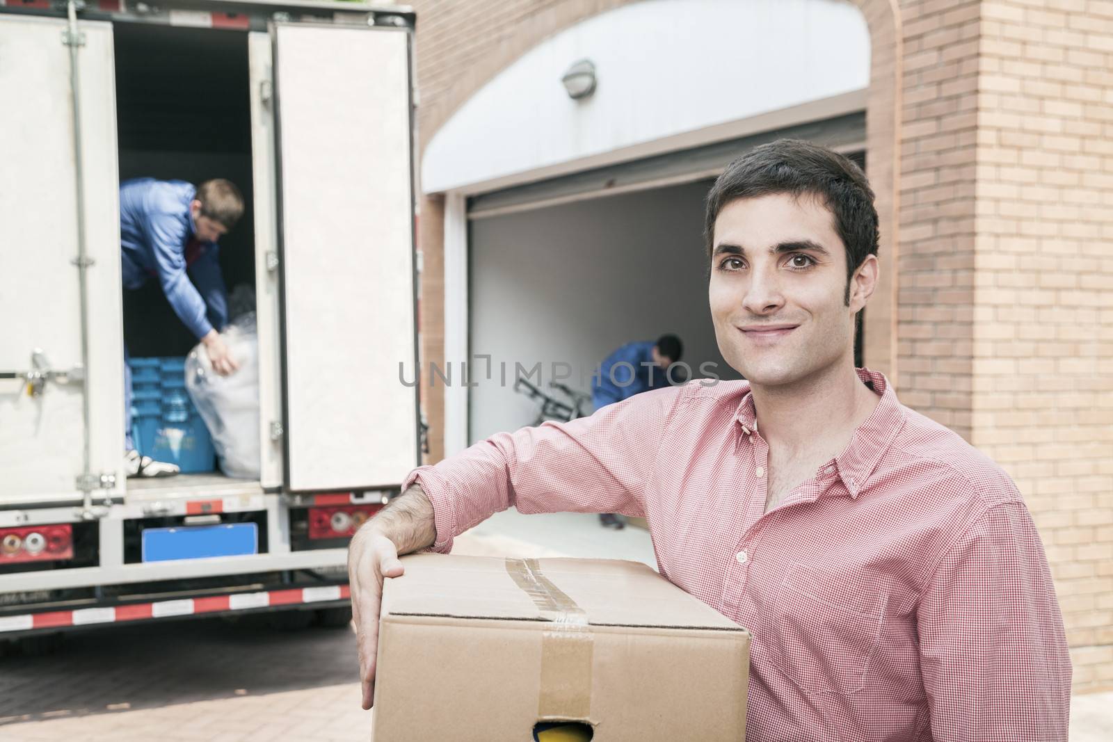 Smiling man holding a cardboard box and moving into his new home
