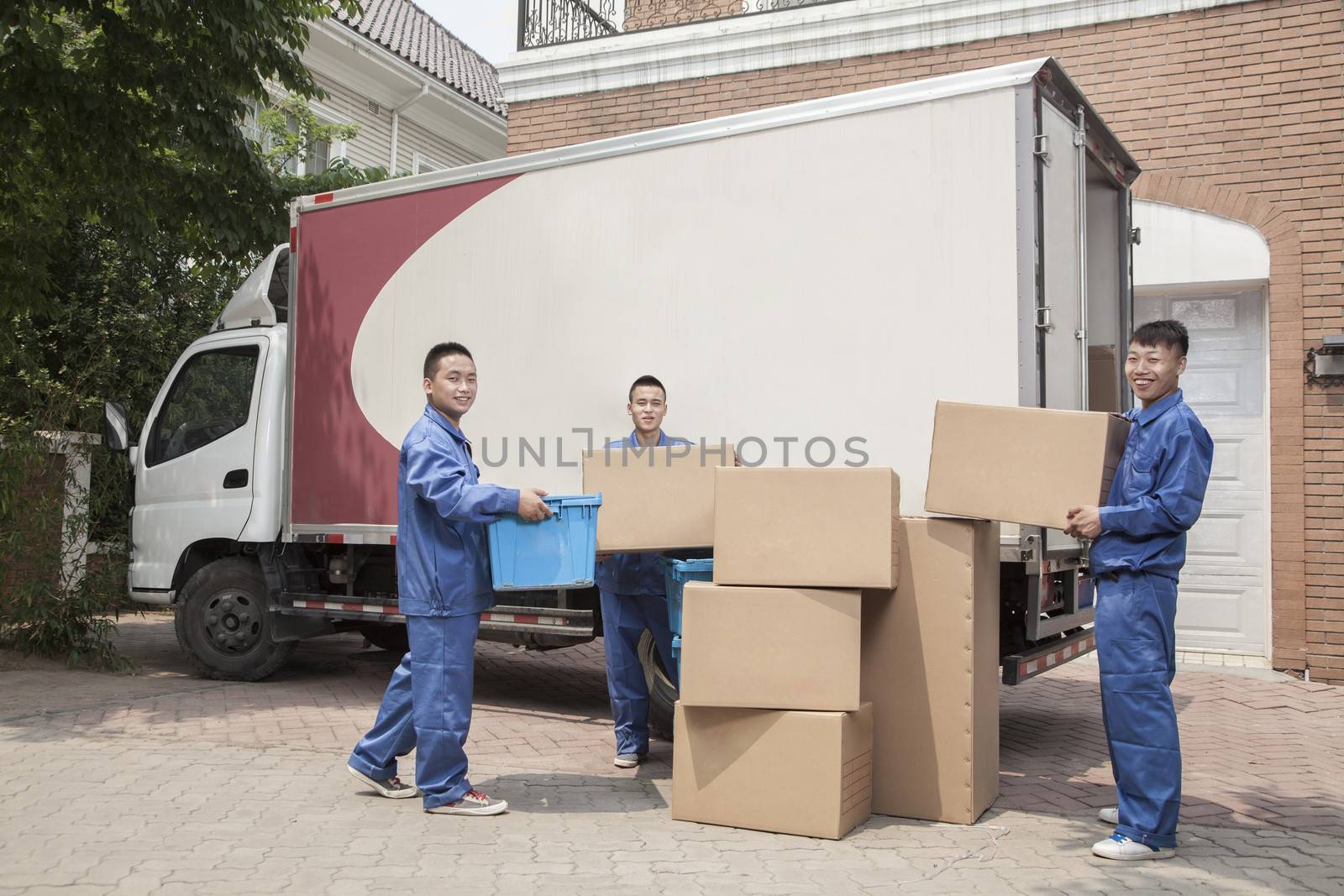 Movers unloading a moving van, many stacked cardboard boxes by XiXinXing